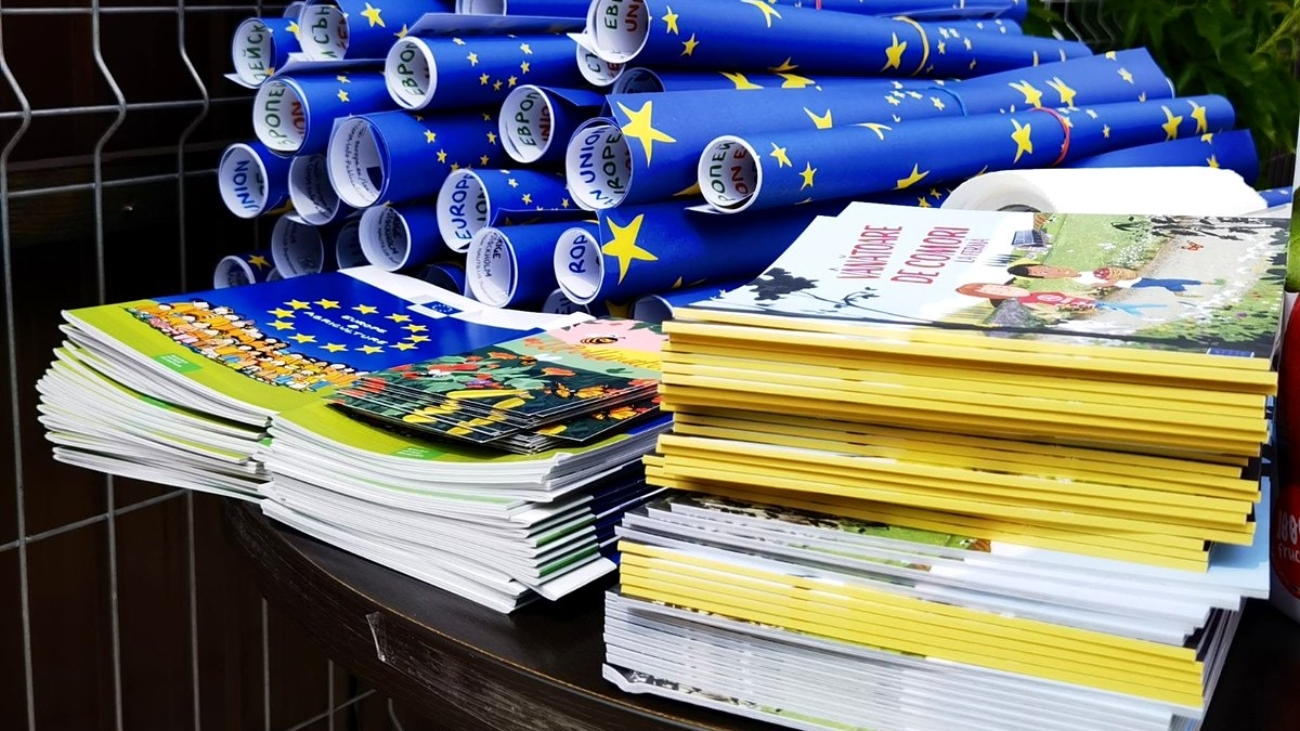 Teanc de publicații europene și postere rulate cu drapelul Uniunii Europene, pregătite pentru distribuire.
