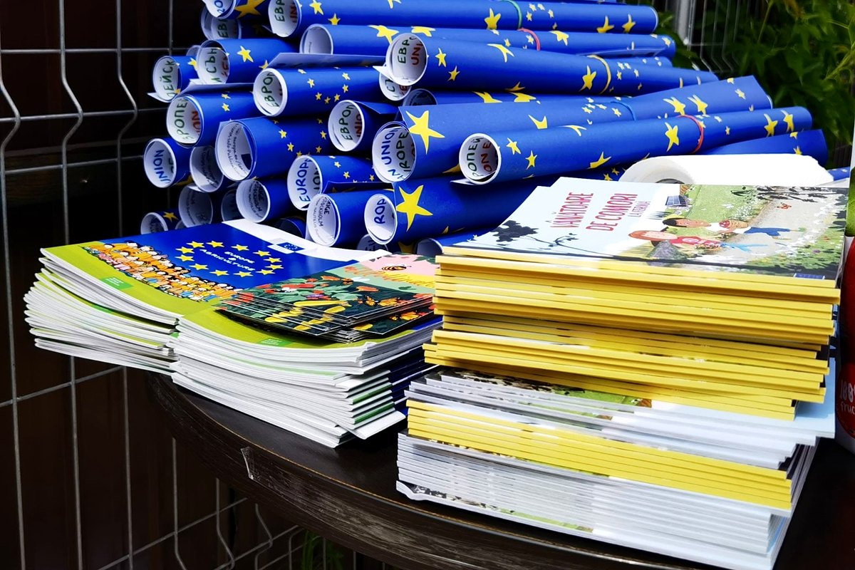 Teanc de publicații europene și postere rulate cu drapelul Uniunii Europene, pregătite pentru distribuire.