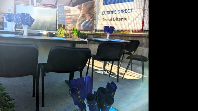 Punct de informare în aer liber, cu mese, scaune și stegulețe ale Uniunii Europene pregătite pentru participanți.