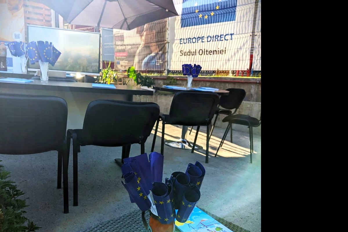 Punct de informare în aer liber, cu mese, scaune și stegulețe ale Uniunii Europene pregătite pentru participanți.
