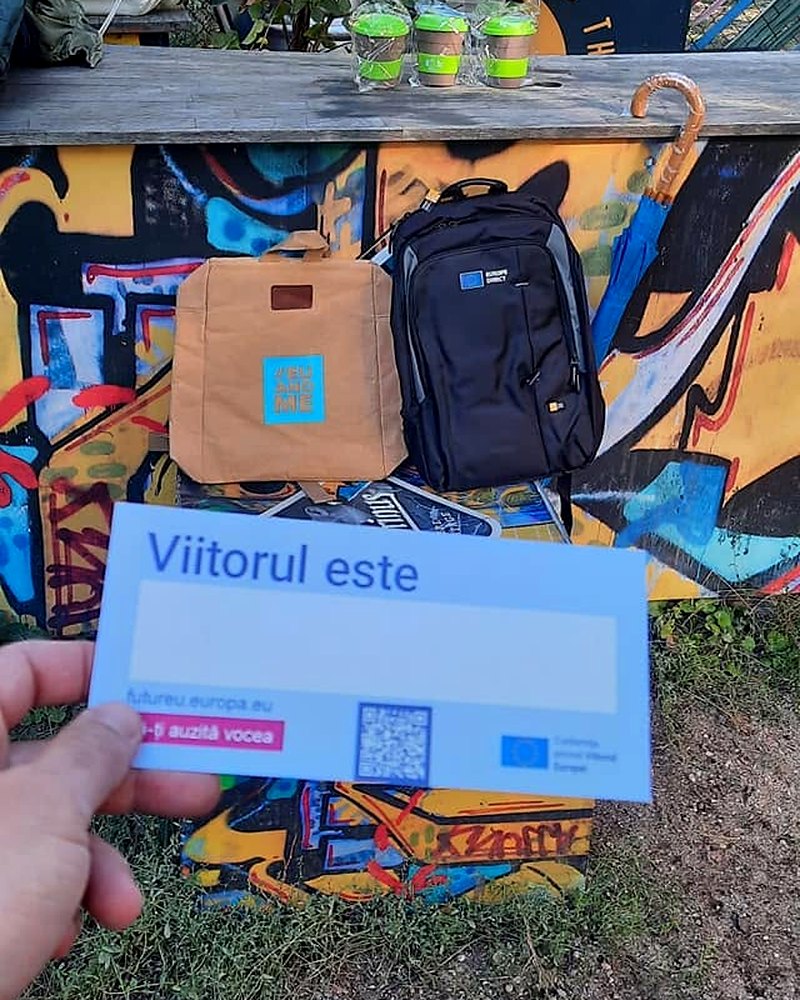 O mână ține un cartonaș albastru pe care scrie „Viitorul este", cu spațiu liber pentru răspunsul cetățeanului.