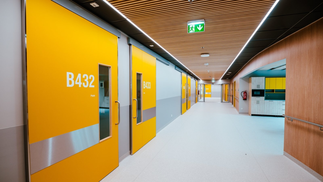Coridor de spital, cu uși galbene și semnalizare